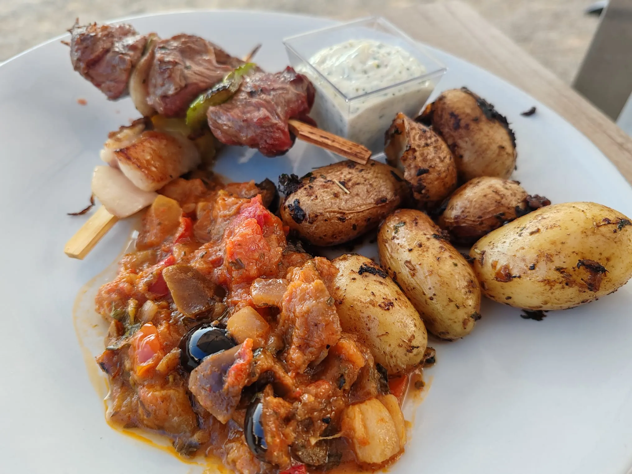 Assiette de brochettes grillées, pommes de terre rôties et légumes à la provençale