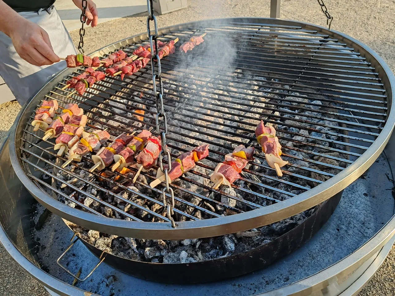 Brochettes de viande et poivrons grillées sur un grand braséro au feu de bois