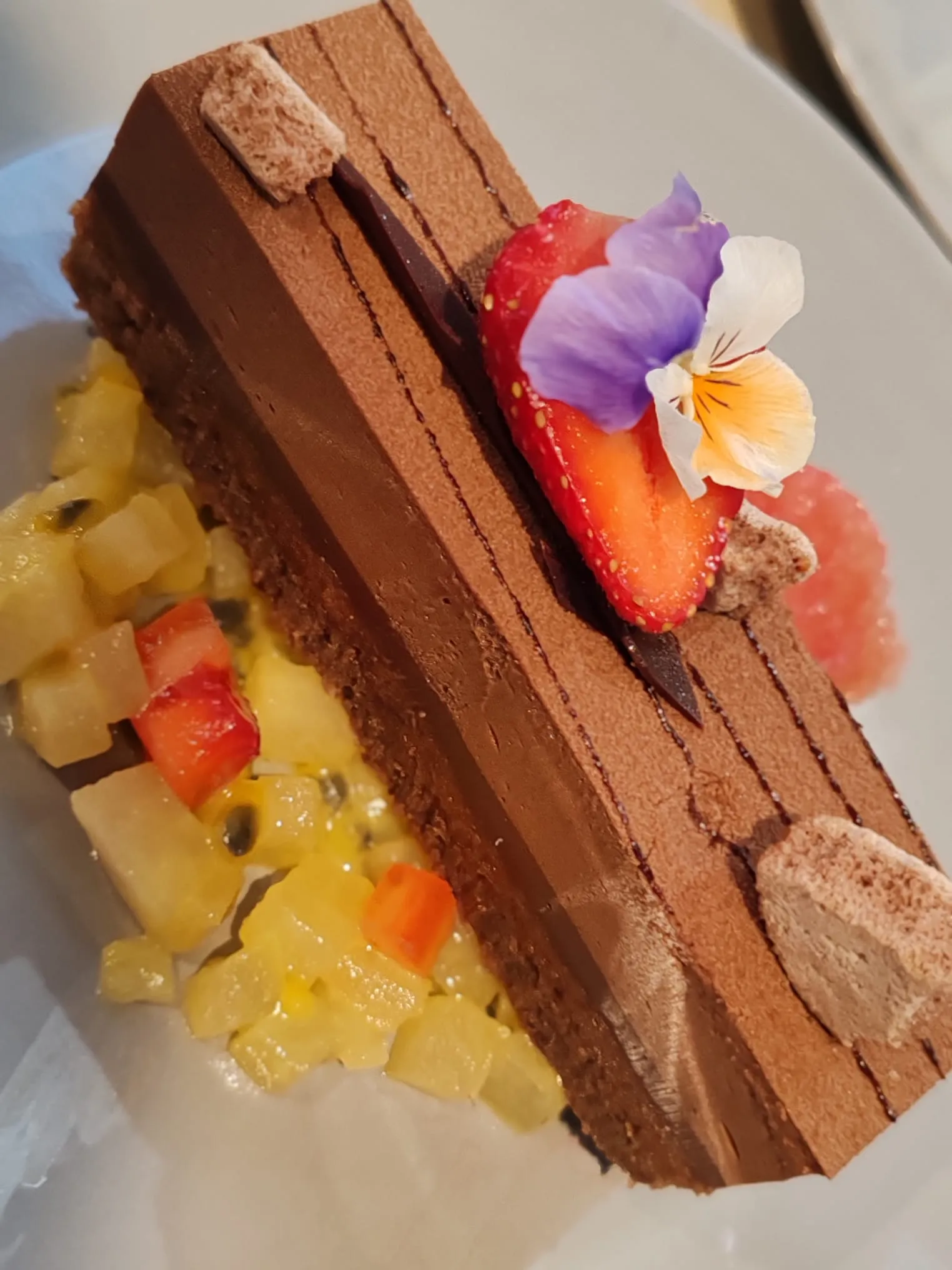 Entremets au chocolat, fraise et pensée comestible, salade de fruits exotiques